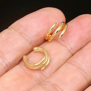 May include: Two gold-toned ear cuffs. The ear cuffs are made of thin metal and are shaped like a spiral. The ear cuffs are designed to be worn on the upper part of the ear.