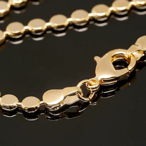May include: A gold chain necklace with a lobster clasp closure. The chain is made of small, round links.