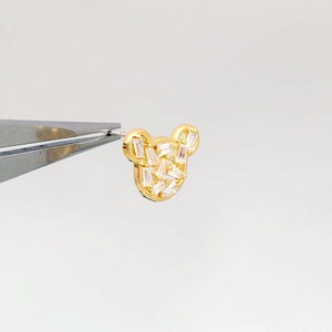 K&ouml;nnte beinhalten: Goldfarbener Ohrring mit einem B&auml;renmotiv, besetzt mit klaren Baguette-Steinen.