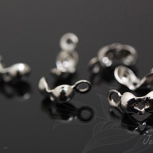 Op de afbeelding: Zilverkleurige metalen sluitingen voor het maken van sieraden. De sluitingen zijn hartvormig met een kleine lus aan één kant.
