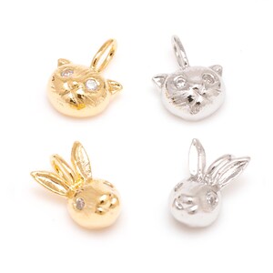 Peut inclure: Quatre petits pendentifs dorés et argentés. Deux pendentifs représentent des visages de chat avec une petite gemme dans chaque œil. Les deux autres sont des visages de lapin. Tous ont une boucle pour suspendre.