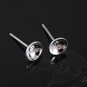 May include: Two silver earring posts with a round, slightly concave, silver top.