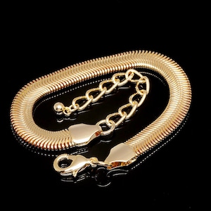 May include: A gold snake chain necklace with a lobster clasp closure. The chain is made of interlocking links that create a snake-like pattern.