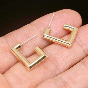 Puede incluir: Un par de pendientes de aro cuadrados de oro. Los pendientes son simples y modernos, con un dise&ntilde;o elegante y minimalista.