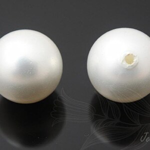 May include: Two white round pearl beads with a hole in the center for stringing.