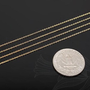 Puede incluir: Cuatro delicados collares de cadena dorados se muestran en diagonal sobre un fondo negro. Se coloca una moneda de veinticinco centavos cerca de las cadenas para comparar el tamaño. Las cadenas están hechas de eslabones pequeños y espaciados uniformemente.