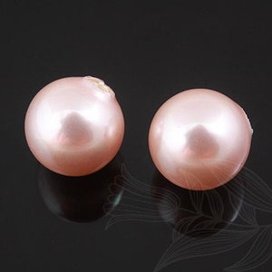 May include: Two round, pale pink pearls with a smooth, glossy finish.