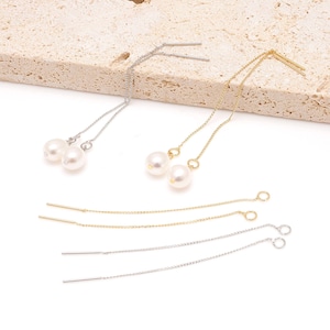 May include: Elegant dangle earrings featuring lustrous white pearls. The earrings are available in both silver and gold tones, with delicate chains and post-style closures. The pearls are round and have a smooth, glossy finish, adding a touch of sophistication.