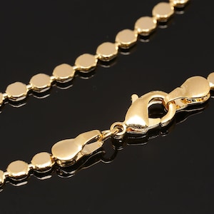May include: A gold chain necklace with a lobster clasp closure. The chain is made of small, round links.