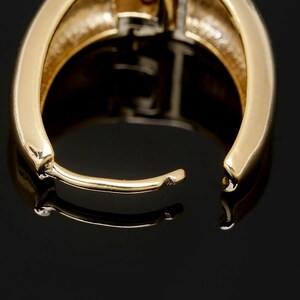 May include: Gold hoop earrings with a smooth, polished finish. The earrings are open and ready to be worn.