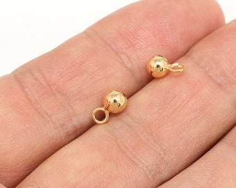 May include: Two gold-colored metal ball charms with a small loop on each. The charms are about 1/2 inch in diameter.