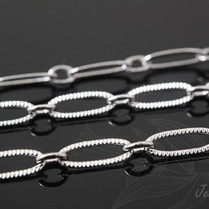 May include: Three silver chains with oval links. The top chain has smooth links, the middle chain has textured links, and the bottom chain has textured links.