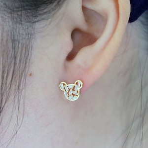 K&ouml;nnte beinhalten: Goldfarbene Ohrstecker in B&auml;renform mit klaren Zirkonia-Steinen.