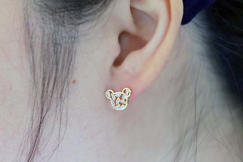 K&ouml;nnte beinhalten: Goldfarbene Ohrstecker in B&auml;renform mit klaren Zirkonia-Steinen.