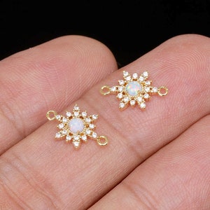 May include: Two gold-tone starburst charms with clear opal stones in the center. Each charm has two jump rings for attaching to jewelry.