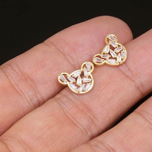 K&ouml;nnte beinhalten: Ein Paar goldfarbene Ohrringe in B&auml;renform mit klaren Zirkonia-Steinen.