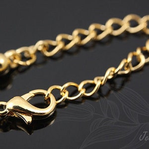 May include: Gold chain extender with a lobster clasp and a ball end. The chain is about 2 inches long.