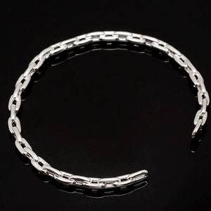 May include: A silver chain bracelet with a simple, linked design. The bracelet is open and ready to be worn.
