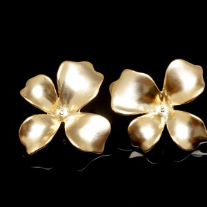 May include: A pair of gold-tone flower-shaped earrings. Each earring features five petals.