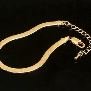 May include: A gold-toned snake chain bracelet with a lobster clasp closure.