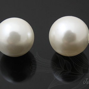 May include: Two white pearl beads, each with a smooth, round surface.