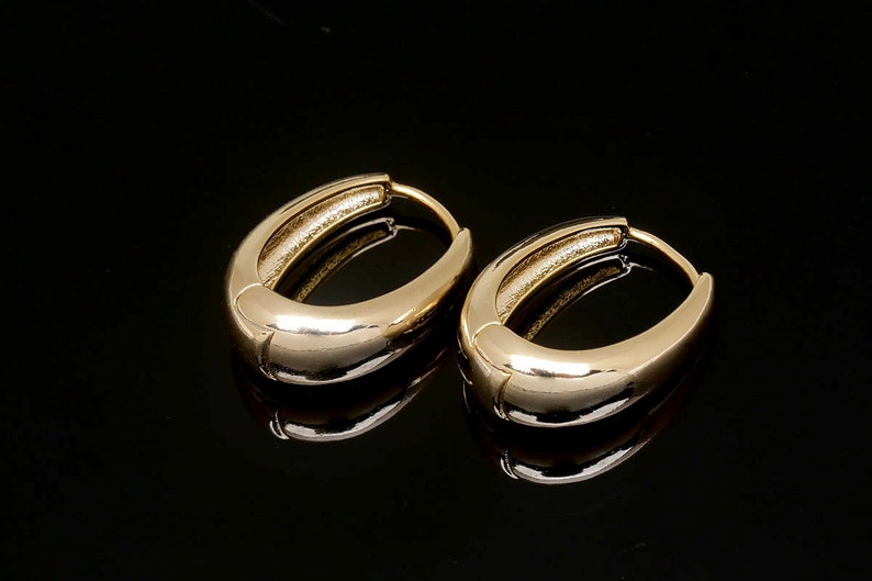May include: A pair of gold oval hoop earrings. The earrings are smooth and shiny.