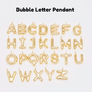 Op de afbeelding: Een verzameling goudkleurige bubble letter hangers, elk met een letter van het alfabet van A tot Z. De hangers worden weergegeven tegen een witte achtergrond. De tekst "Bubble Letter Pendant" staat bovenaan.