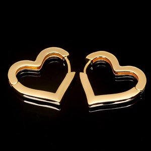 May include: A pair of gold heart-shaped hoop earrings. The earrings are simple and elegant, and would make a great gift for any occasion.