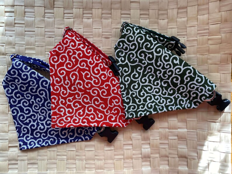 Puede incluir: Tres collares para mascotas en azul, rojo y verde, cada uno con un patr&oacute;n de remolino blanco. Los collares tienen hebillas de pl&aacute;stico negro y anillas en D de metal. Se muestran sobre una superficie tejida.