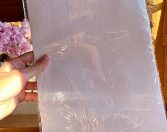 May include: A white sheet of paper wrapped in clear plastic packaging. The paper is smooth and appears to be a type of craft paper.