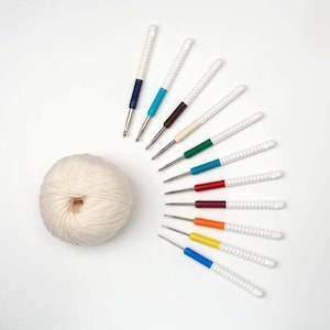 May include: A set of 10 colorful crochet hooks with white handles and a ball of white yarn. The hooks are arranged in a semi-circle around the yarn.