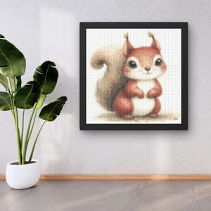 May include: A framed cross-stitch artwork featuring a cute squirrel. The squirrel has red and white fur, a fluffy tail, and large, expressive eyes. The artwork is set against a white background and framed in a black square frame.