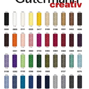 Peut inclure: Nuancier de fils à coudre Gütermann creativ. Les bobines sont disposées en rangées, présentant une large gamme de couleurs, du noir au bleu clair. Le nom de la marque est en haut, avec le mot "creativ" en rouge.