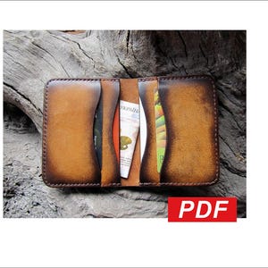 Puede incluir: Cartera de cuero marrón abierta, con múltiples ranuras y compartimentos para tarjetas. La cartera contiene tarjetas y billetes. Los bordes de la cartera son de un marrón más oscuro. La palabra "PDF" está en un rectángulo rojo en la esquina inferior derecha.