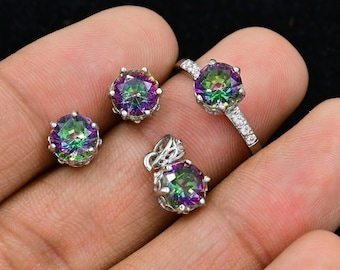 Può includere: Un set di gioielli in argento con un anello, orecchini e un ciondolo. Ogni pezzo presenta una pietra preziosa rotonda e iridescente con un arcobaleno di colori.