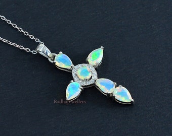 May include: A silver necklace with a cross pendant featuring a central opal surrounded by smaller opals and clear cubic zirconia stones. The pendant is on a silver chain.