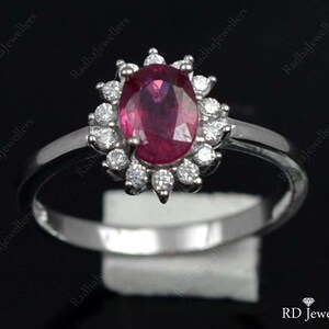 Pu&ograve; includere: Un anello d'argento con un grande rubino ovale circondato da un'aureola di diamanti pi&ugrave; piccoli.