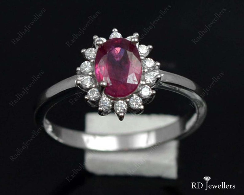 Pu&ograve; includere: Un anello d'argento con un grande rubino ovale circondato da un'aureola di diamanti pi&ugrave; piccoli.