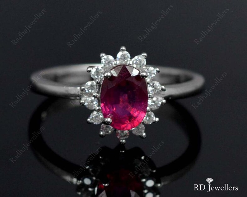 Pu&ograve; includere: Un anello d'argento con un grande rubino ovale circondato da un'aureola di diamanti pi&ugrave; piccoli.