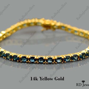 May include: A gold tennis bracelet with blue gemstones. The bracelet is made of 14k yellow gold and features a classic tennis chain design.