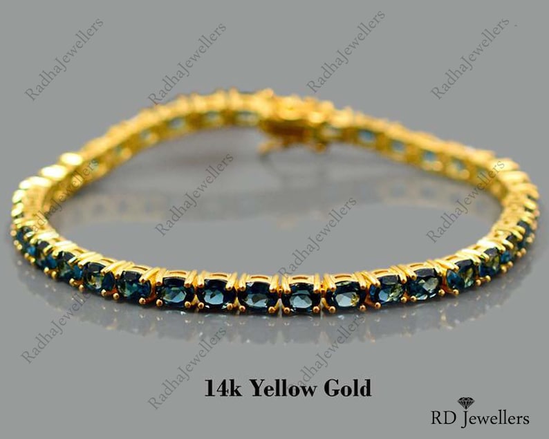 May include: A gold tennis bracelet with blue gemstones. The bracelet is made of 14k yellow gold and features a classic tennis chain design.