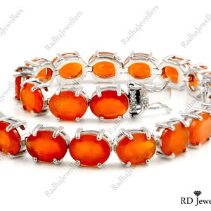 May include: A silver bracelet featuring a row of oval-shaped orange gemstones. The bracelet has a clasp fastening.