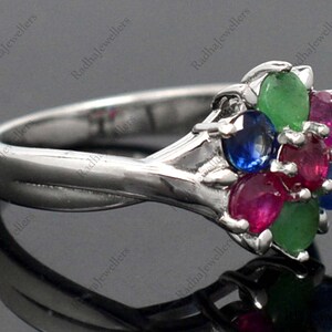 May include: A silver ring featuring a cluster of five oval-shaped gemstones in shades of red, blue, and green. The ring is set in a silver band.