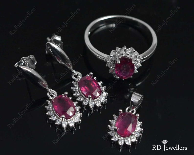Pu&ograve; includere: Un set di gioielli in argento con accenti di rubino e diamanti. Il set comprende un anello, un ciondolo e un paio di orecchini. Le pietre di rubino sono di un colore rosso intenso e i diamanti sono chiari e scintillanti.  RD Jewellers