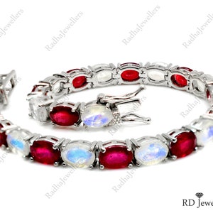 May include: A silver bracelet featuring alternating oval-cut red gemstones and iridescent moonstones. The bracelet is connected by a silver clasp and is displayed on a white surface. The jewelry is from RD Jewellers.