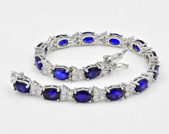May include: A silver tennis bracelet with oval-shaped blue sapphires and smaller clear diamonds set in the metal.