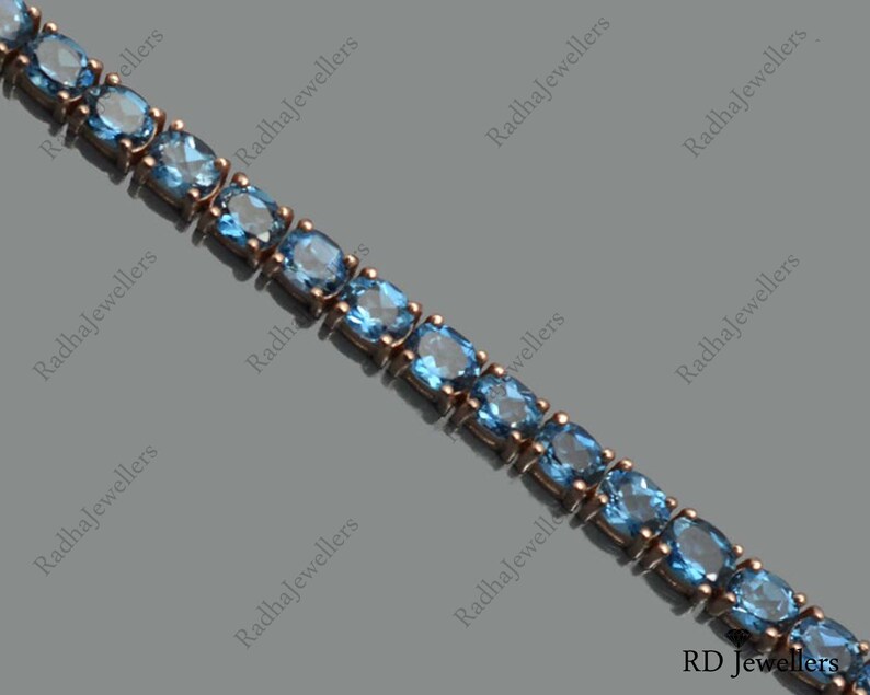 May include: A delicate silver chain bracelet with a row of light blue oval-shaped gemstones. The bracelet is made of sterling silver and features a classic design.