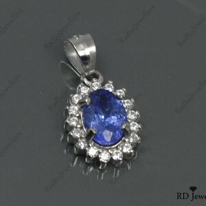 May include: A silver pendant with a blue oval gemstone surrounded by smaller white gemstones.