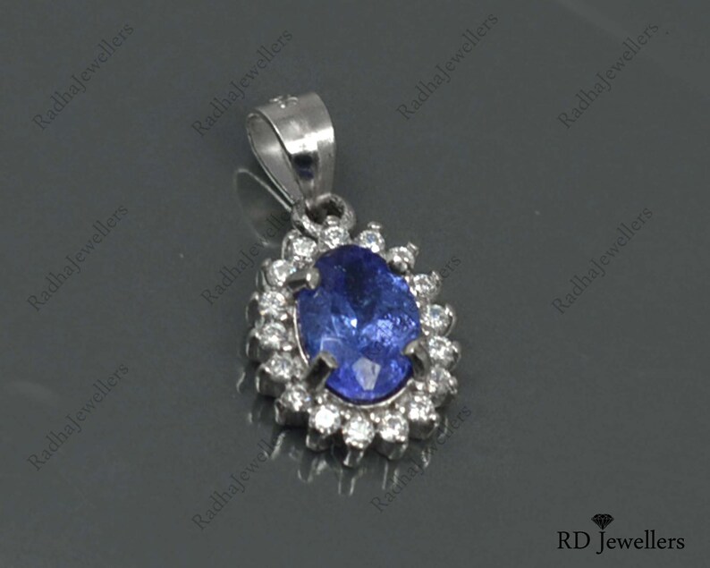 May include: A silver pendant with a blue oval gemstone surrounded by smaller white gemstones.