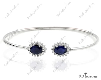 Puede incluir: Un brazalete de plata con dos piedras de zafiro azul ovaladas engastadas en un halo de piedras de circonita cúbica transparentes.